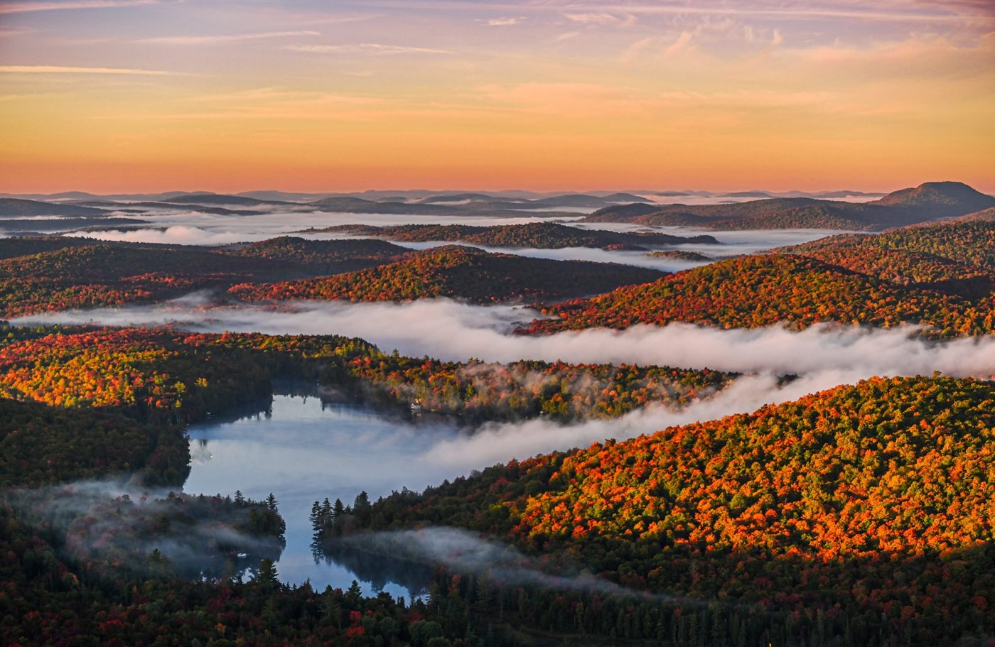 Sunrise over Adirondack foliage and a mist-covered lake